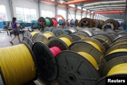 A woman walks in an electricity cable factory in Baoying, Jiangsu province, China, July 23, 2006.