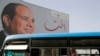 FILE - People ride on a bus as posters with Egypt's President Abdel Fattah al-Sissi are displayed in Cairo, Egypt. 