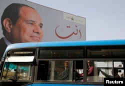 FILE - People ride on a bus as posters with Egypt's President Abdel Fattah al-Sissi are displayed in Cairo, Egypt, March 25, 2018.