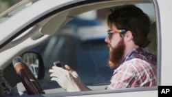 FILE - An man works his phone as he drives through traffic in Dallas, Tuesday, Feb. 26, 2013. Texas lawmakers are considering a statewide ban on texting while driving. (AP Photo/LM Otero)
