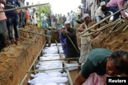 Rohingya refugees who died after their boat capsized, as they were fleeing Myanmar, are buried in a mass grave just behind Inani Beach near Cox's Bazar, Bangladesh, Sept. 29, 2017.