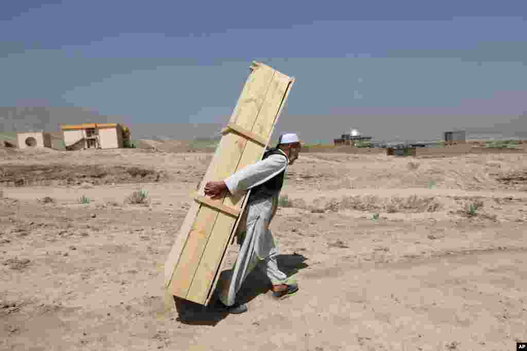 A man carries an empty casket for a funeral ceremony, in Kabul. Afghanistan held a national day of mourning, a day after a suicide bomber killed at least 80 people who were taking part in a peaceful demonstration in Kabul. The attack was claimed by the Islamic State group.