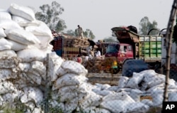 FILE - Pakistan laborers unload sacks of onion imported from neighboring India at Pakistani border Wagah near Lahore Pakistan, May 14, 2013.