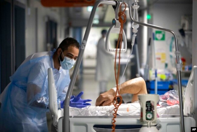 A medical staff member speaks with a COVID-19 patient in the infectious disease ward of the Strasbourg University Hospital, eastern France, Jan. 13, 2022. (AP Photo/Jean-Francois Badias)