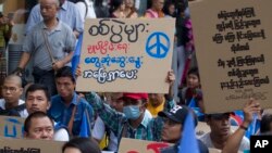 FILE - Activists shout slogans and brandish placards demanding a stop to the war, as they take part in a rally for peace, May 12, 2018, Yangon, Myanmar.