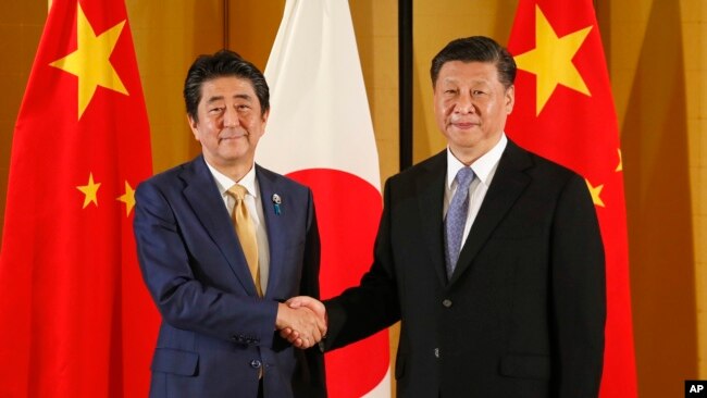资料照:中国国家主席习近平和大阪与日本首相安倍晋三握手。(2019年6月27日)
