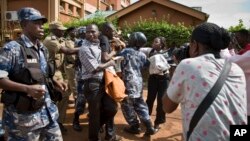 FILE - Reporters and members of Uganda's Human Rights Network for Journalists struggle with police during a protest in downtown Kampala, Uganda, May 28, 2013.