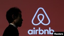 Seorang pria melewati logo Airbnb, situs penyewaan penginapan (foto: ilustrasi). 