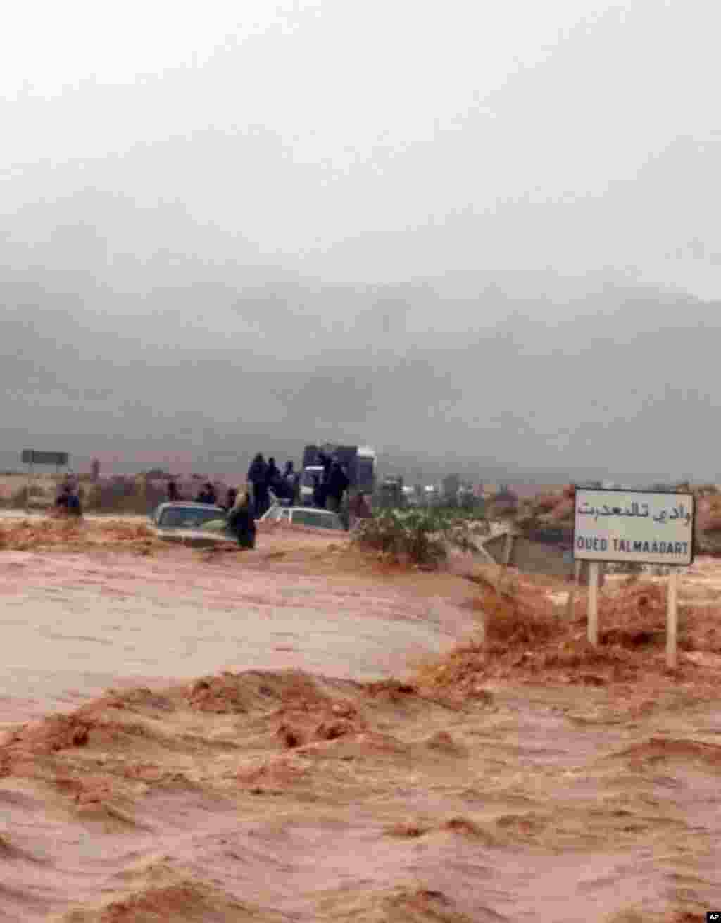 Cette image prise avec un téléphone portable montre résidents de Guelmim, au sud ouest du Maroc, des passagers sont coincés sur des véhicules bloqués par la montée des eaux, lundi 24 novembre 2014.