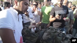 A Lebanese red cross worker, left, takes an injured French U.N. peacekeeper into an ambulance after a bomb explosion targeted a convoy of French soldiers in the southern port city of Sidon, July 26, 2011