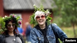 Para remaja putri mengenakan hiasan bunga di kepala saat perayaan musim panas di Helsinki, Finlandia, 22 Juni 2018.