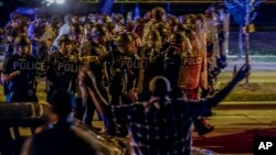 미국 밀워키에서 경찰이 흑인 청년을 총격살해한 사건에 항의하는 시위가 14일 이틀째 계속됐다. 시위진압경찰이 돌을 던지는 시위대에 맞서 전진하고 있다.