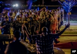 Police move in on a group of protesters throwing rocks at them in Milwaukee, Sunday, Aug. 14, 2016.