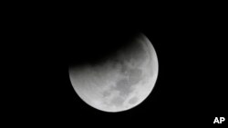 ARSIP – Foto bertanggal 28 Agustus 2018 menunjukkan bayangan bumi mulai menyelimuti bulan dalam sebuah gerhana bulan total yang tampak d Jakarta, Indonesia (foto: AP Photo/Tatan Syuflana)