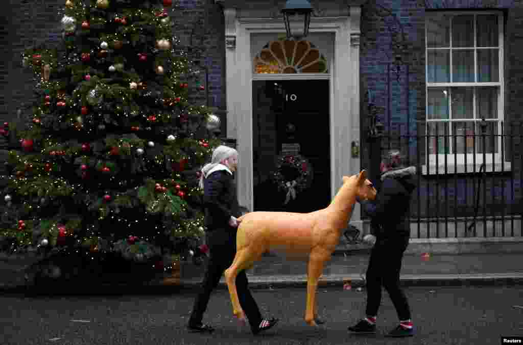 Two young women carry a model reindeer past 10 Downing Street in London, Britain.