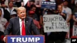 FILE - Republican presidential candidate Donald Trump speaks at a rally as a man holds up a sign that reads "Islamophobia is not the answer" in Oklahoma City, Feb. 26, 2016.