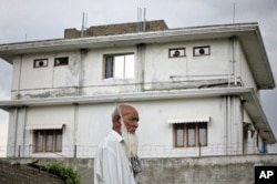 FILE - A resident walks past the compound where U.S. Navy SEAL commandos killed al-Qaida leader Osama bin Laden in Abbottabad, May 5, 2011.