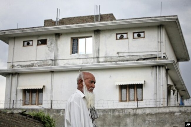 FILE - A resident walks past the compound where U.S. Navy SEAL commandos killed al-Qaida leader Osama bin Laden in Abbottabad, May 5, 2011.