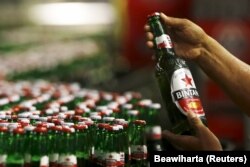 Seorang pekerja PT Multi Bintang Indonesia Tbk. memegang sebotol bir Bintang untuk pengecekan kualitas di sebuah pabrik bir di Jakarta 17 April 2015. (Foto: REUTERS/Beawiharta)