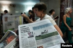 FILE - An employee distributes newspapers, with a photograph on the left side of the page of former U.S. spy agency contractor Edward Snowden, at an underground walkway in central Moscow, July 2, 2013.