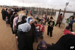 FILE - Syrian women wait in line to receive winter aid as U.N. General Assembly President Mogens Lykketoft visits the Zaatari refugee camp in Mafraq, Jordan, Jan. 20, 2016.