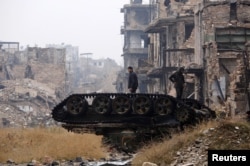 Forces loyal to Syria's President Bashar al-Assad stand atop a damaged tank near Umayyad mosque, in the government-controlled area of Aleppo, Syria, during a media tour Dec. 13, 2016.