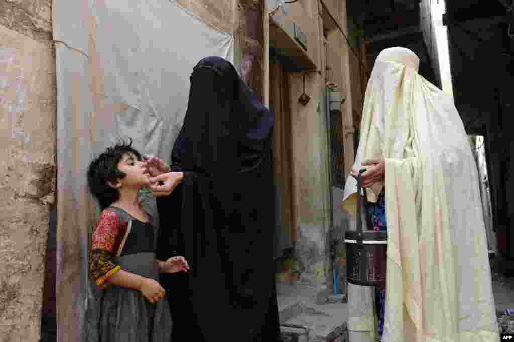 Petugas kesehatan Pakistan memberikan vaksin polio kepada seorang anak di kota Bannu. 