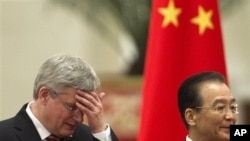 Canadian Prime Minister Stephen Harper, left, rubs his forehead while walking with Chinese Premier Wen Jiabao during a welcoming ceremony at the Great Hall of the People in Beijing Wednesday, Feb. 8, 2012. (AP Photo/Alexander F. Yuan)