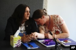 Relatives of military personnel killed during the Iraq War, Rose Gentle, left, and Sarah O'Connor react during a news conference after John Chilcot presented The Iraq Inquiry Report at the Queen Elizabeth II Centre in London, July 6, 2016.