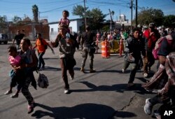 Migrants run toward the U.S. after breaking past a line of Mexican police at the Chaparral border crossing in Tijuana, Mexico, Nov. 25, 2018, near the San Ysidro, California, entry point.