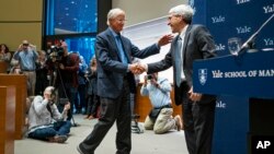 Peter Salovey, President of Yale University, right, welcomes Yale University Professor William Nordhaus, one of the 2018 winners of the Nobel Prize in economics, to the podium, Oct. 8, 2018, in New Haven, Conn.