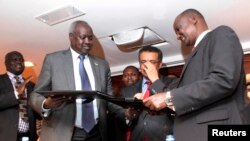 South Sudan's leader of the government's delegation Nhial Deng Nhial (L) exchanges a signed ceasefire agreement with the head of the rebel delegation Gen. Taban Deng Gai (R).