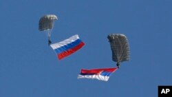 FILE - Serbian soldiers parachute from a Mi-8 transport helicopter with a Russian, left, and Serbian flags during joint Russian-Serbian military exercices at Nikinci training ground, 60 kilometers west of Belgrade, Serbia, Nov. 14, 2014.