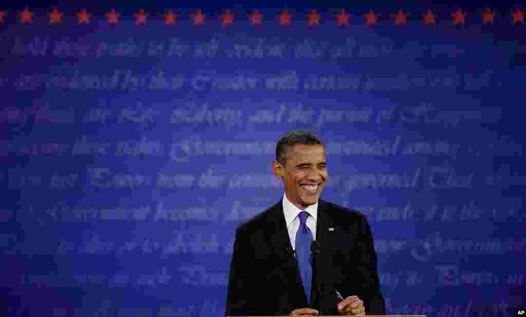 Le pr&eacute;sident Obama souriant au mod&eacute;rateur du d&eacute;bat, Jim Lehrer 