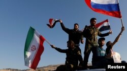 Syrians wave Iranian, Russian and Syrian flags during a protest against U.S.-led air strikes in Damascus, Syria April 14,2018.