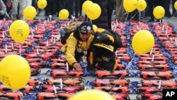 An unidentified mother of a high school student among 304 victims of sunken ferry Sewol in 2014 places a light stick on a life vest symbolizing the victims before a candle light vigil in Seoul, South Korea, Jan. 7, 2017.