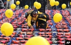 FILE - An unidentified mother of a high school student among 304 victims of sunken ferry Sewol in 2014 places a light stick on a life vest symbolizing the victims before a candle light vigil in Seoul, South Korea, Jan. 7, 2017.