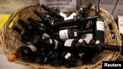 A basket with bottles of wine for sale are seen at a wine store in Buenos Aires, Argentina, Nov. 8, 2017. The sign reads "Red wine on discount per bottle."