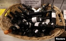 A basket with bottles of wine for sale are seen at a wine store in Buenos Aires, Argentina, Nov. 8, 2017. The sign reads "Red wine on discount per bottle."