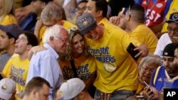 Democratic presidential candidate Sen. Bernie Sanders, left, has his photo taken with fans at the NBA basketball Western Conference finals between the Golden State Warriors and the Oklahoma City Thunder in Oakland, California, May 30, 2016.