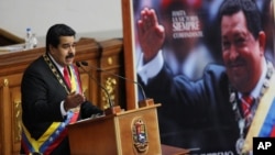 FILE - Venezuela's President Nicolas Maduro, left, speaks next to a framed poster featuring the late President Hugo Chavez, during the annual state-of-the-nation address at the National Assembly in Caracas, Venezuela, Jan. 21, 2015.