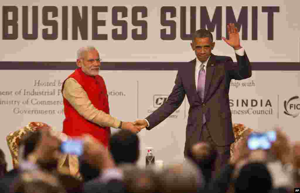 U.S. President Barack Obama, right waves to the audience as he and Indian Prime Minister Narendra Modi attend the India-U.S business summit in New Delhi, India, Jan. 26, 2015. 