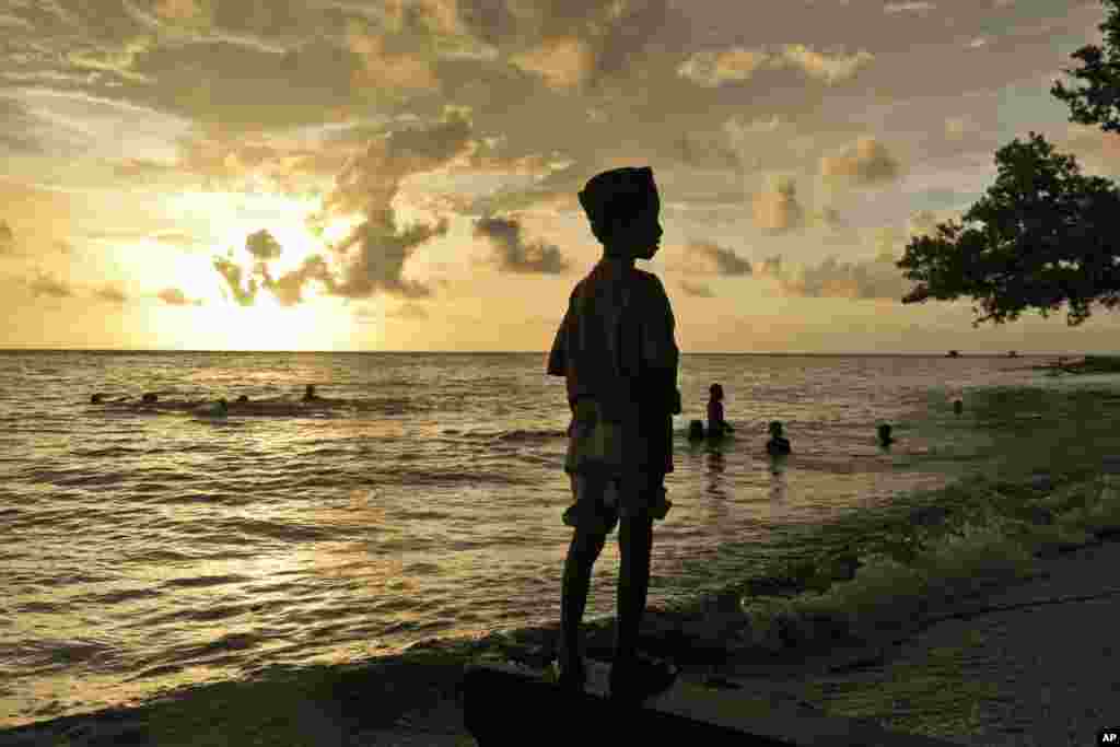 Seorang bocah laki-laki berdiri di pantai Kastela saat matahari terbenam di Ternate, Maluku.