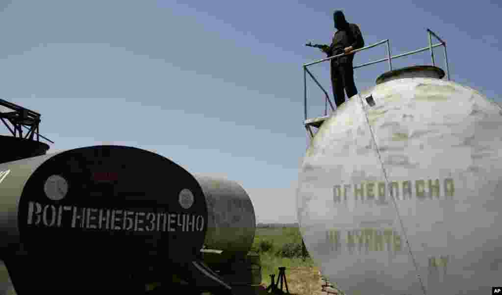 An armed man of the Donbass Battalion, a volunteer militia group that has stated its intent to fight in support of Ukrainian unity, is on patrol, standing atop a storage tank with a sign &quot;Flammable - Don&#39;t smoke&quot; at their base in the eastern Ukraine village of Velyka Novosilka, May 16, 2014.
