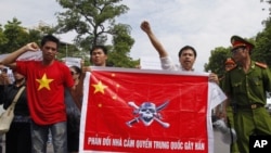 Policemen look at protesters holding a Chinese flag with a picture of a pirate skull and crossbones during an anti-China demonstration in Hanoi, July 3, 2011.