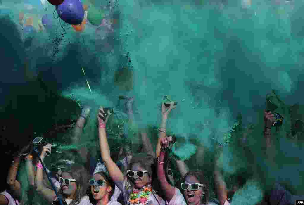 Runners covered in colored powder dance after taking part in the Color Run of Sevilla, Spain.