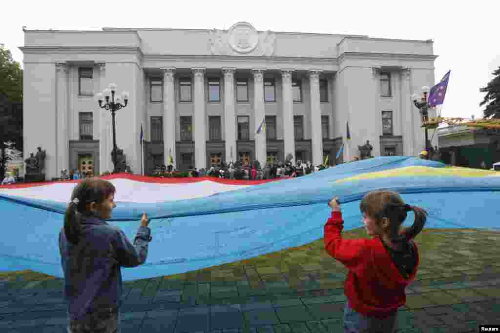 People hold a combined Ukrainian-Crimean flag during a pro-Ukrainian rally in front of the parliament building in Kyiv, June 5, 2014. 
