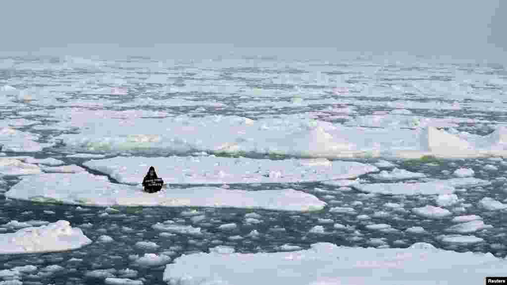 Environmental activist and campaigner Mya-Rose Craig, 18, holds a cardboard sign reading &quot;youth strike for climate&quot; as she sits on the ice floe in the middle of the Arctic Ocean, hundreds of miles above the Arctic Circle.