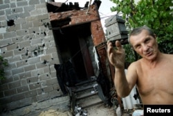 A local resident shows the damage done to his home near the airport in Donetsk, Ukraine, Sept. 13, 2017.