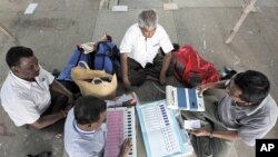 Polling officers check Electronic Voting Machines (EVM) after collecting them from a distribution centre ahead of the third phase of polls in Kolkata April 26, 2011.